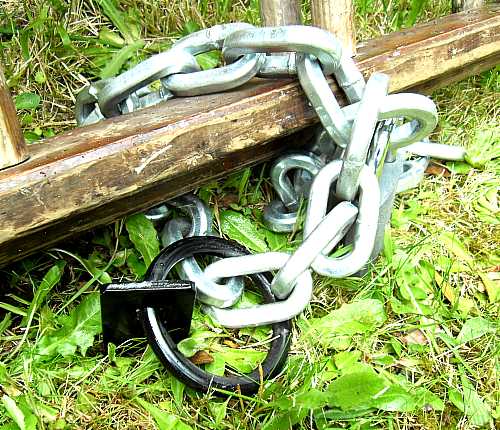 Ancrage au sol, chaîne et cadenas sur échelle en bois. Gros plan